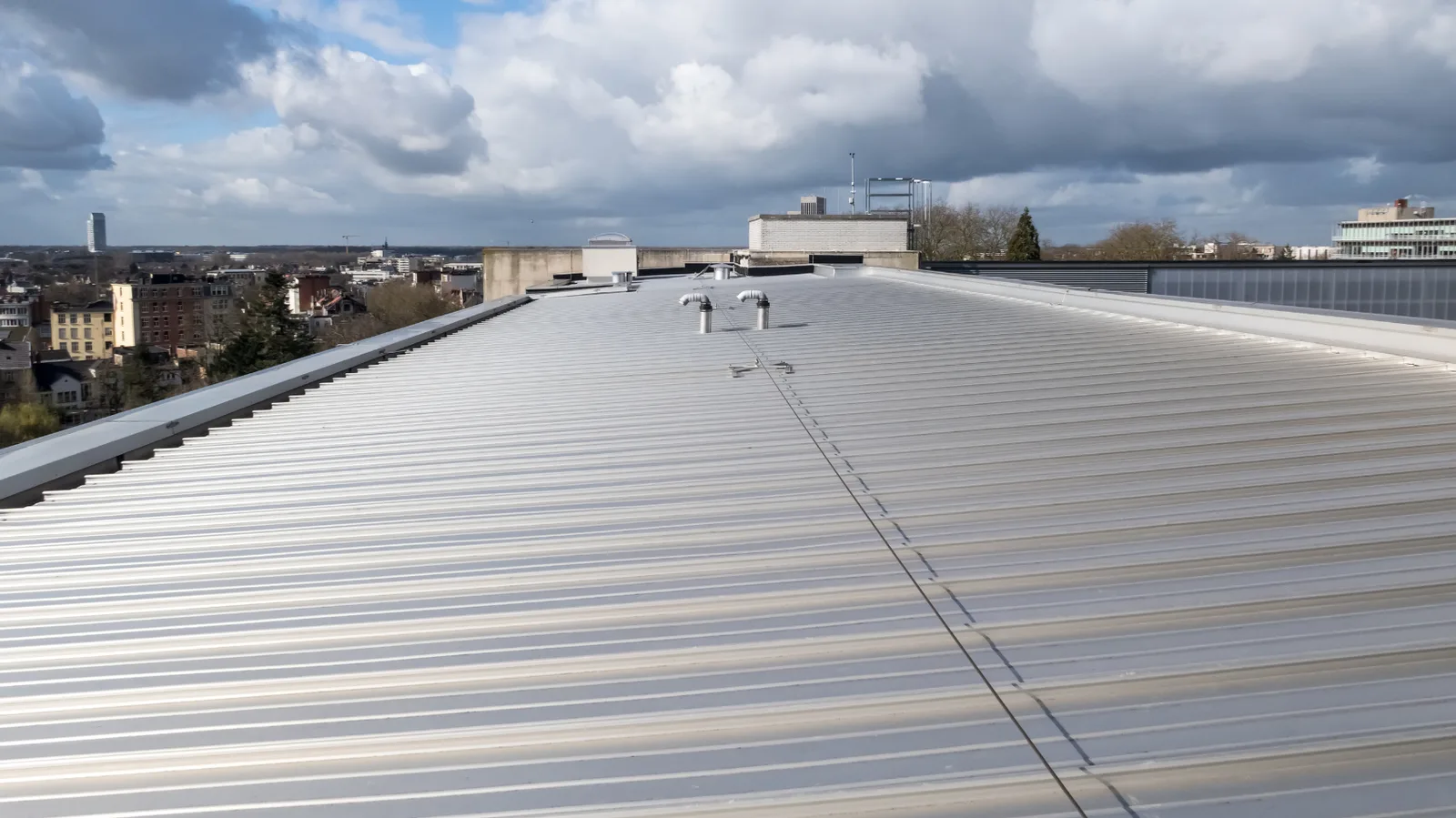 Long metal roof of a commercial building overlooking a city skyline